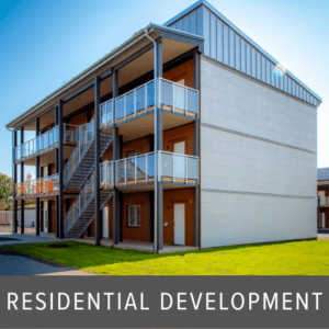 Multiple balconies with glass balustrades and dark posts on a three-storey apartment building with external stairs and a mix of wood and panel cladding.