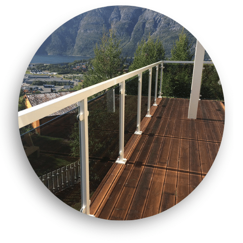 Glass windbreak with white powder-coated posts and clamps on a dark timber deck, offering open views of the valley and distant mountains.