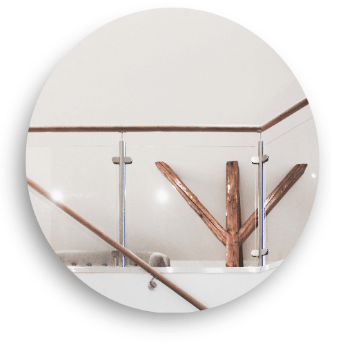 Interior glass railing with stainless steel posts and timber top rail, surrounding an open area and adding warmth through natural wood accents.