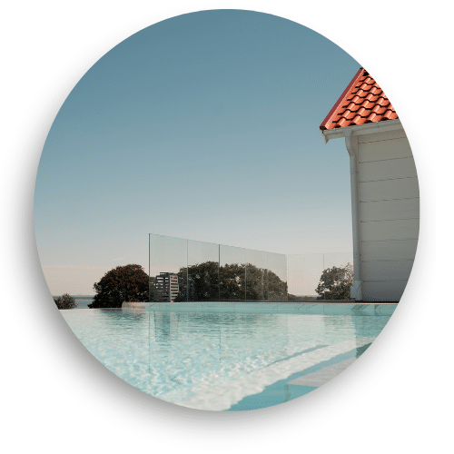 Sleek frameless glass railing surrounding a pool, offering clear, unobstructed views and an elegant frame toward the landscape and horizon.