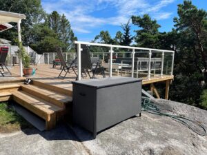 White aluminium glass railing on multi-level timber deck with stairs, surrounded by natural greenery and seating zones.