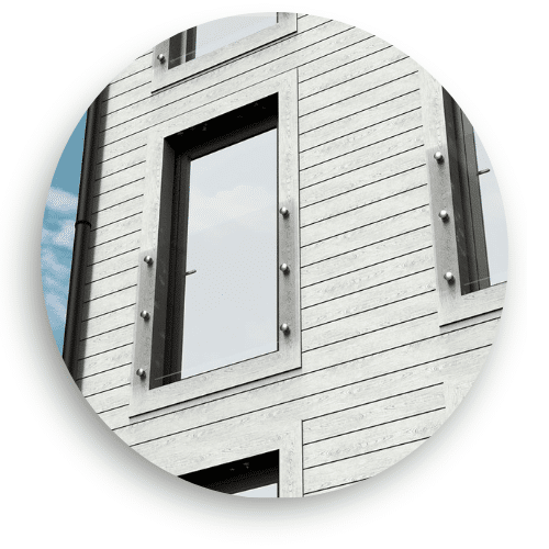 Stainless steel French balcony with glass panels mounted in front of full-height glazed doors on a modern wooden façade.