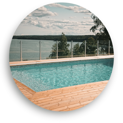 Glass fence with aluminium posts surrounding a timber-decked pool, providing safety while maintaining an open view of the lake landscape.