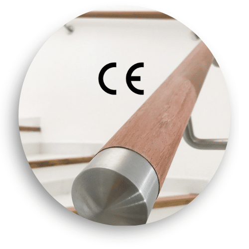 Close-up of a CE-marked timber handrail with stainless steel end caps. Mounted on a white staircase with matching metal wall brackets for a clean, secure grip.