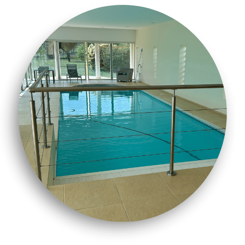 Indoor pool area with minimalist stainless steel wire railing and handrail, offering a safe and stylish barrier in a modern setting.