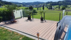 Raised terrace with a mix of frosted and clear glass railing enclosing the pool area, combined with tropical palm trees and sweeping landscape views.