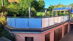 Elevated timber terrace with frosted glass and round stainless steel posts, surrounded by garden and sunroom.