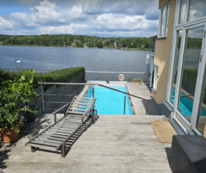 Horizontal wire railing in stainless steel securing a wooden pool deck with lake view – discreet, safe and modern for split-level terraces.