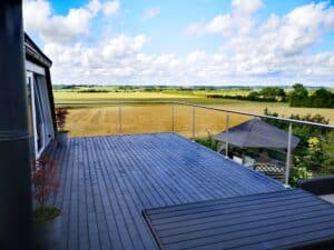 Modern wire rope balustrade on dark timber decking, ideal for garden terraces with sweeping landscape vistas.