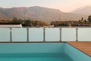 Frosted safety glass railing by terrace pool with scenic mountain backdrop and warm sunset lighting, offering wind and privacy protection.