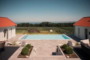 Minimalist glass pool balustrade without posts, offering uninterrupted views of ocean, orchards and rolling hills from the poolside.