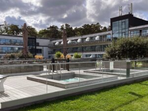 Elegant laminated glass railing with round posts around city hotel pool, combining modern safety with a sleek, professional finish.