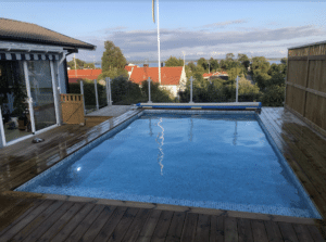 White aluminium glass balustrade around elevated villa pool with decking and sea view – a clean and child-safe outdoor solution.