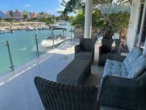 Stainless steel glass balustrade installed on deck with views of canal, boats and colourful houses in a tropical setting.