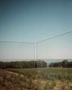 Close-up of minimalist glass pool fence without posts, with open view over coastline and farmland – ideal for modern infinity pools.