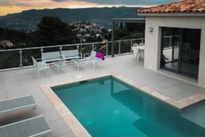 Framed glass safety railing around pool and terrace in hillside villa at sunset – secure yet open design in a luxurious setting.