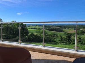 Stainless steel post glass balustrade on balcony, offering uninterrupted views over green meadows and open countryside.